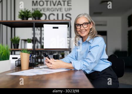 Woman head office worker in a stylish office with a smile sitting at the table and looking at the camera Stock Photo