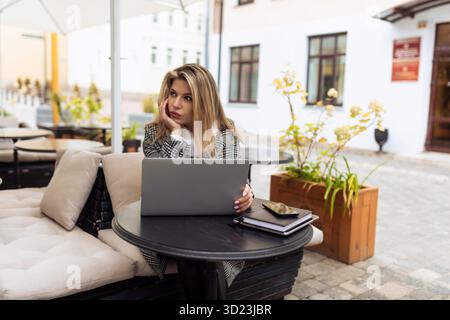 Adult woman bank worker working online on laptop in city cafe Stock Photo