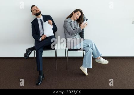 Office employees sit on chairs man and woman waiting for an interview Stock Photo
