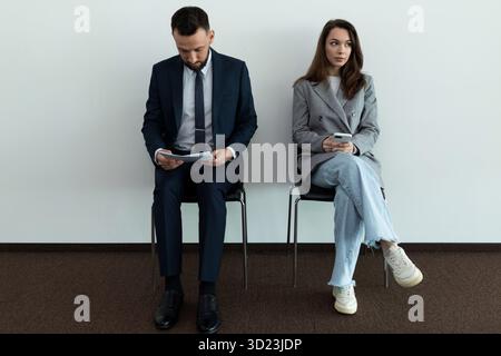 Two young professionals in business suits waiting in line for an interview Stock Photo