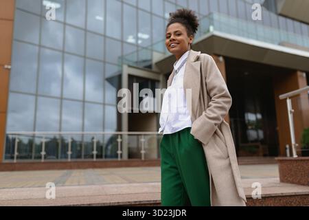 African american woman economist on financial work against the backdrop of a non-modern office building outside looking at the c Stock Photo