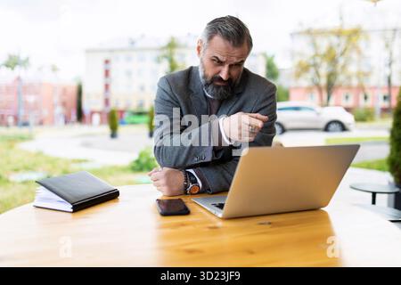 Fifty serious male businessman working on a laptop in a street cafe Stock Photo