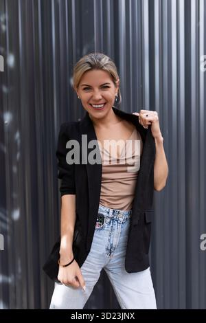 Young middle-aged woman dancing with a smile looking at the camera against the backdrop of an office wall Stock Photo