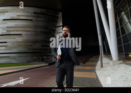 Businessman rushing to meet him talking on the phone with a laptop in his hands Stock Photo