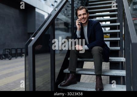 Portrait of a strong successful business man sitting on the steps of an office building Stock Photo