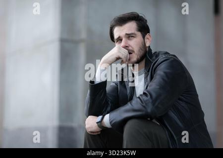 A depressed man sits with a lost mood looks in prostration Stock Photo