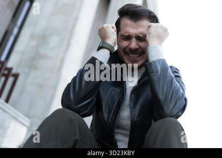 A man at the time of a panic attack sits in the city on the steps Stock Photo