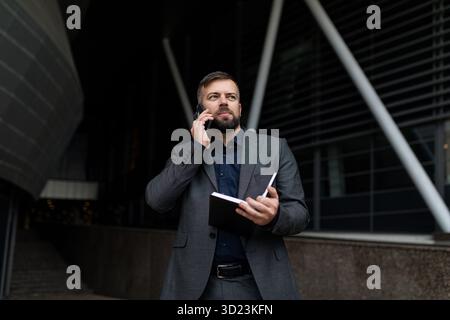Portrait of a successful adult male businessman talking on a mobile phone outside the office, business economic consultant conce Stock Photo