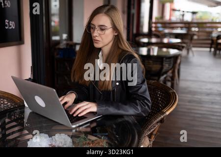 Young woman working on a laptop in a city cafe Stock Photo