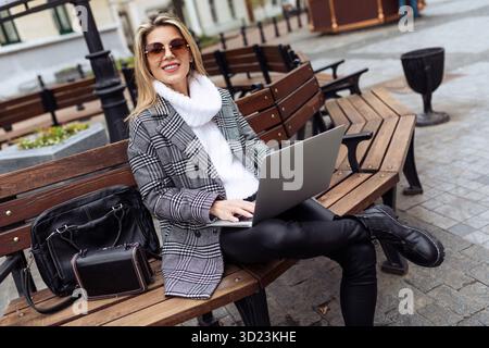 Adult successful woman entrepreneur working on laptops in city square online Stock Photo