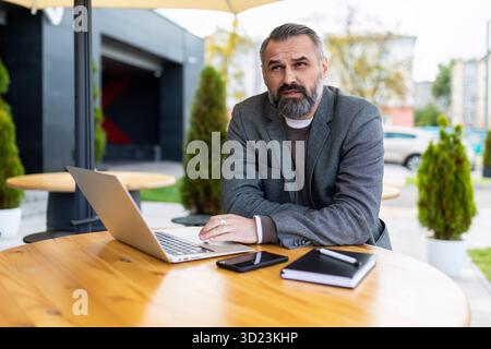 Adult male businessman with beard working on laptop outside Stock Photo