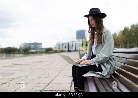 Young strong woman freelancer software developer working on laptop outside Stock Photo