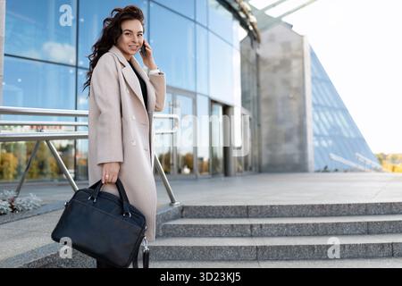 Portrait of a successful business modern woman with a mobile phone on the background of the office, woman leader in business con Stock Photo