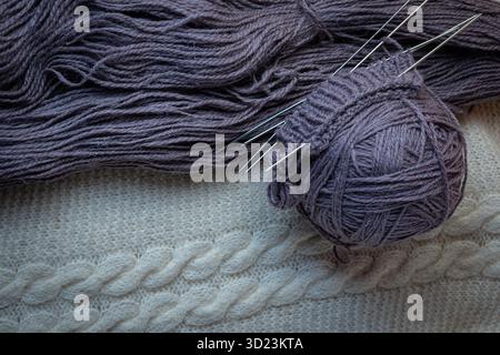 A ball of purple wool and knitting needles on a white background. Stock Photo