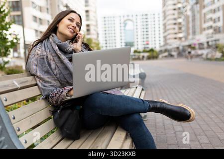 Successful female freelancer working online outdoors on laptop, Concept of remote work Stock Photo