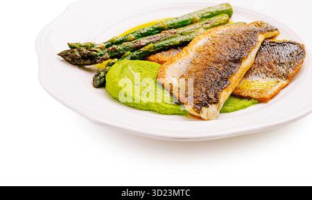 Grilled fish served with vibrant green puree and asparagus on a plate Stock Photo