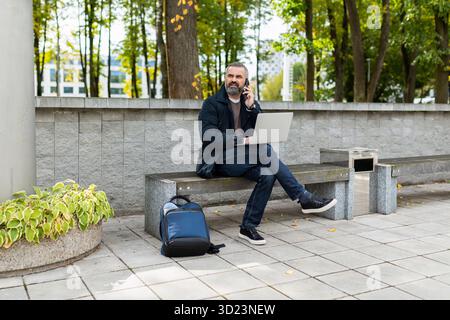 Adult male freelancer working on laptop while sitting in park Stock Photo