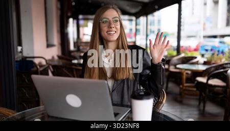 Young woman student working online in a cafe on a laptop with a cup of coffee Stock Photo