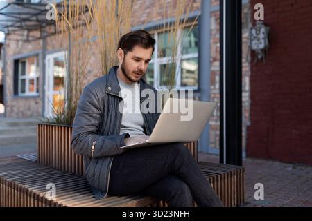 Man working on laptop outside online Stock Photo
