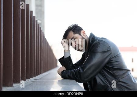 A man with a mental illness who is depressed holds his head and looks away prostration Stock Photo