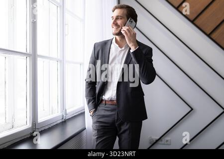 Young businessman talking on a mobile phone looking out the window in the office Stock Photo