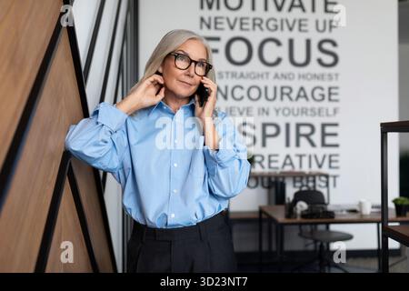 Portrait of successful Middle aged older business woman executive with mobile phone in the office, concept of successful busines Stock Photo