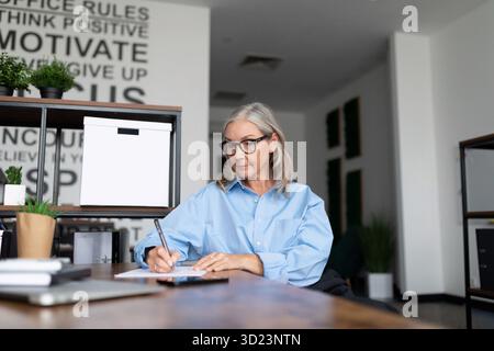 Middle aged older business woman of European appearance works as a manager in the office, concept of successful business develop Stock Photo