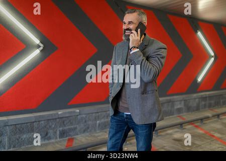 Portrait of a serious ambitious successful mature male businessman with a mobile phone against the background of red arrows Stock Photo