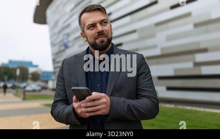 Presentable male businessman holding phone outside Stock Photo
