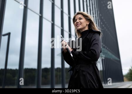 Concert of a successful businessman woman who is in a hurry on business with a mobile phone with a smile on her face Stock Photo