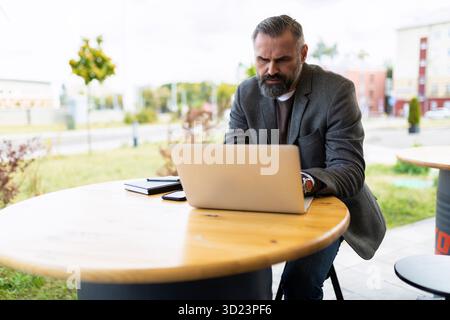 Mature male entrepreneur working online in cafe on laptop Stock Photo