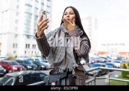 Stylish young woman talking on video call outside Stock Photo