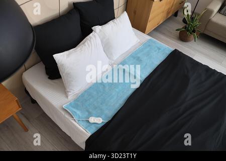 Electric heating pad on big bed in room, top view Stock Photo