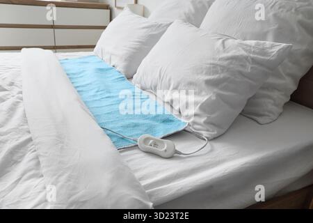 Blue electric heating pad on bed in room Stock Photo