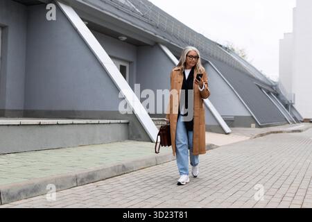 Mature business woman walking talking on the cell phone Stock Photo