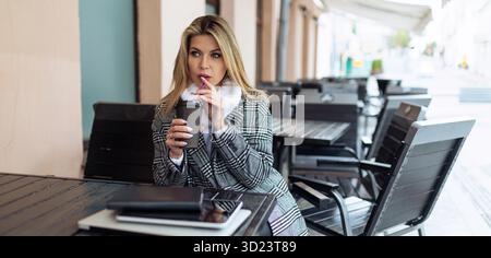 Woman at the table drinking coffee in a city cafe Stock Photo