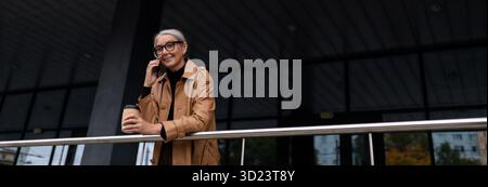 Elderly business woman talking on mobile phone outside Stock Photo