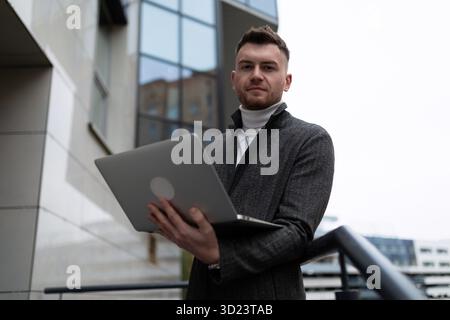 Portrait of a young businessman with a laptop outside the office Stock Photo