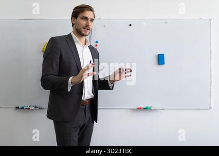Businessman in a formal suit in front of a whiteboard in the office explains to colleagues in a business development strategy Stock Photo