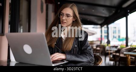 Woman freelancer working online on laptop in city cafe Stock Photo