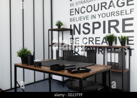 Empty office with desk with stationery and flowers on shelves in the background Stock Photo