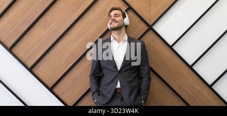Satisfied businessman in business suit listening to music with headphones with pleasure Stock Photo