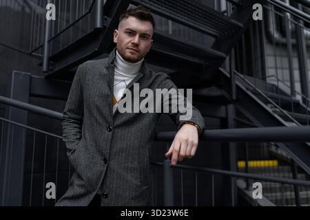 Stylish young caucasian he man in autumn coat on black stairs outside Stock Photo