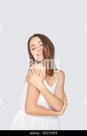 Young caucasian female smiling in white dress with eyes closed and long brown Stock Photo