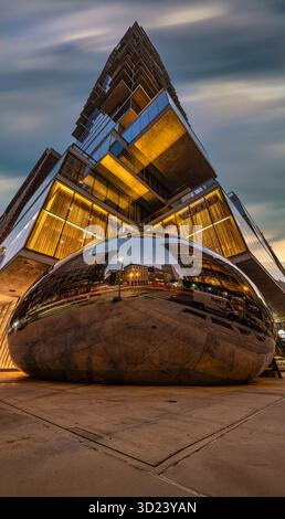 Modern building with striking architecture and reflective sculpture under dynamic sky. New York City, NY, USA Stock Photo