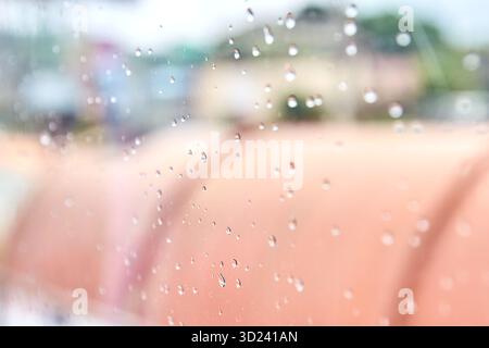Raindrops on glass with blurred urban background on a cloudy day Stock Photo