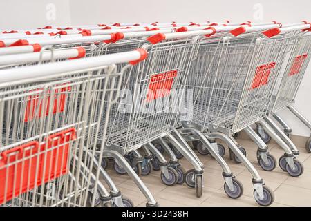 Rows of empty shopping carts aligned in a supermarket aisle on a tiled floor Stock Photo
