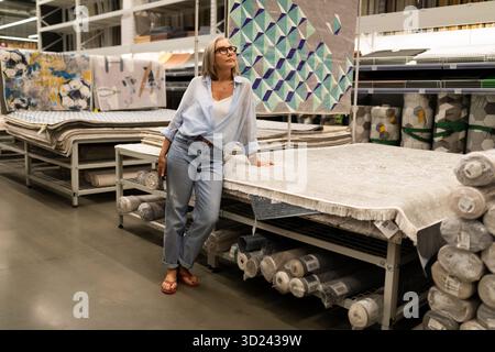 Woman exploring fabric selection in a modern craft store during the afternoon Stock Photo