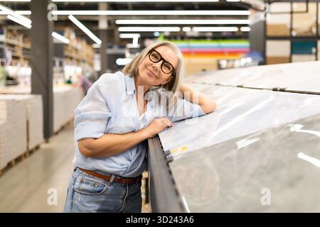 Smiling woman in glasses enjoys browsing materials in a modern home improvement store Stock Photo