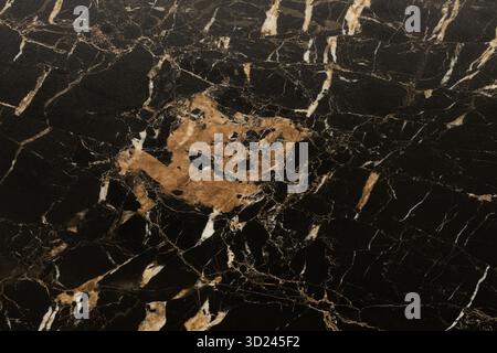 Black marble surface with intricate golden and white veining details showcases natural beauty and elegance for design purposes Stock Photo